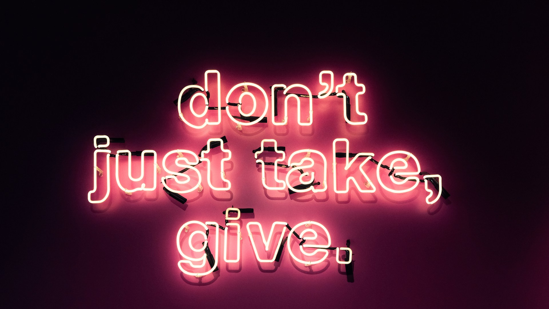 Neon sign reads "don't just take, give." This illustrates the question of whether authors should give their books away for free.