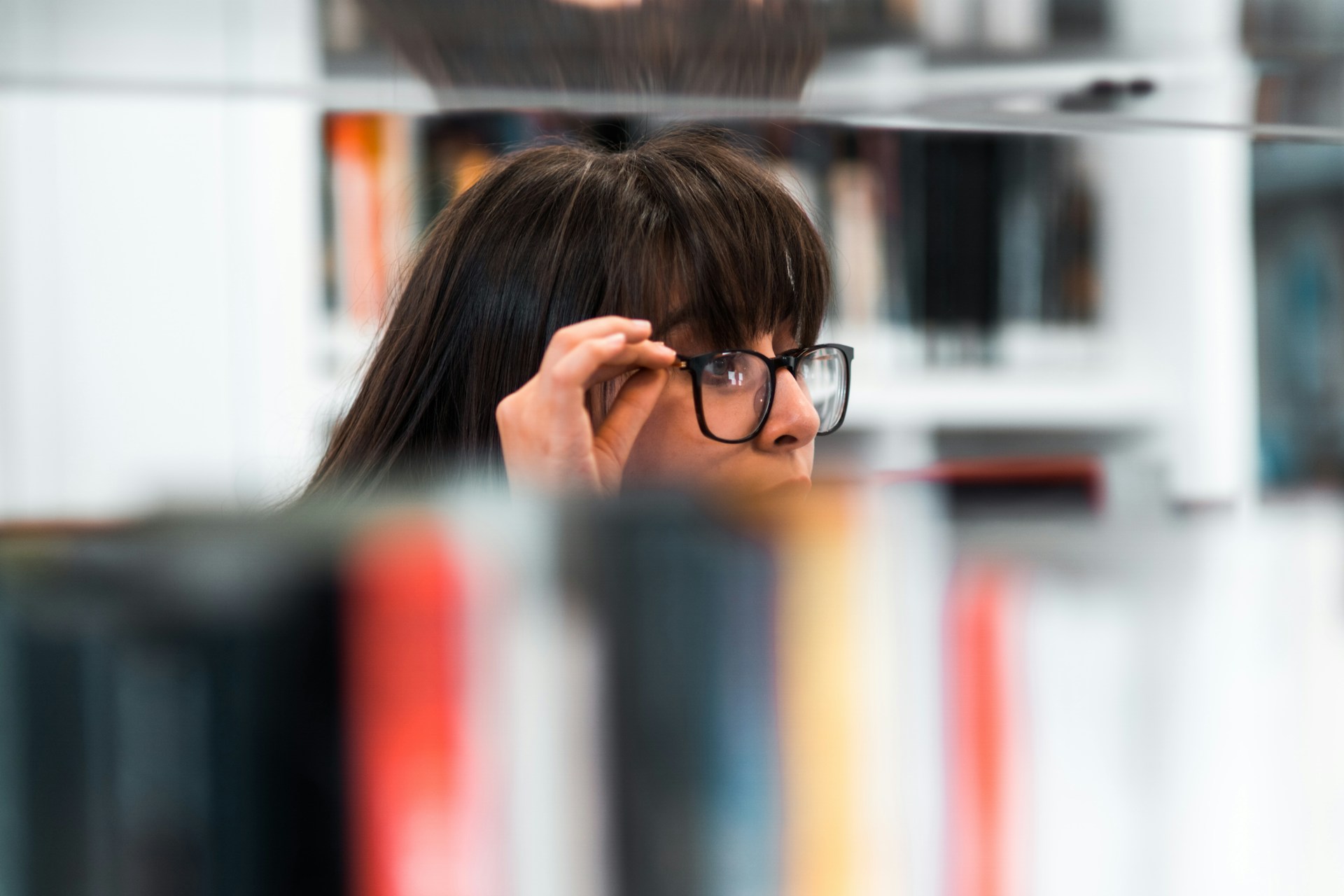 Image shows a woman looking intently at a bookshelf. Purpose is to illustrate the topic of the blog, What do you find yourself doing?